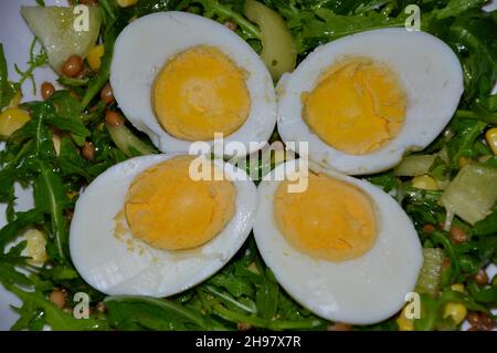 Boiled eggs sliced on arugula and pepper salad. Vegetarian meal. Stock Photo
