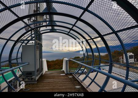 Metal tunnel bridge with wooden walkway.Strong metal bars bridge in shape of tunnel with wooden walkway and round floor lights on both sides.circular Stock Photo