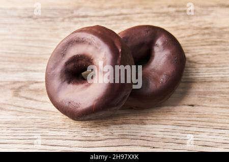Two delicious chocolate doughnuts on a wooden surface Stock Photo