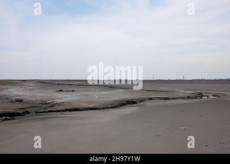 Lake of dry mud formed from a mud volcano eruption in Sidoarjo, Indonesia. Clouds in blue sky. Natural disaster in oil and gas industry and geology. Stock Photo