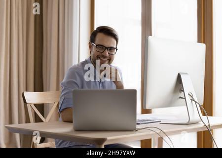 Happy confident professional man working at laptop and desktop Stock Photo
