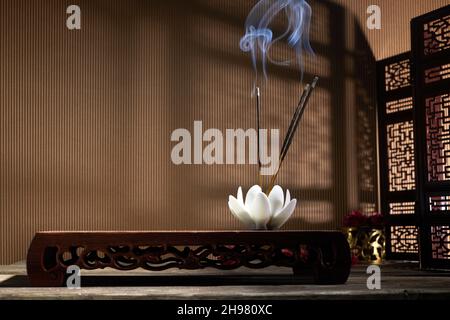 Smoke from burning incense sticks standing on lotus incense holder Stock Photo