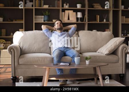 Happy satisfied remote employee resting on comfortable sofa Stock Photo