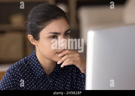 Focused pensive Indian professional working at computer from home Stock Photo