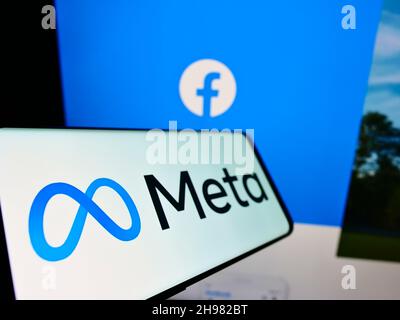 Smartphone with logo of US technology company Meta Platforms Inc. on screen in front of Facebook emblem. Focus on center-left of phone display. Stock Photo