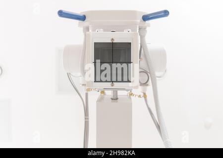 X-ray department in modern hospital. Radiology room with scan machine with empty bed. Technician adjusting an x-ray machine. Scanning chest, heart Stock Photo