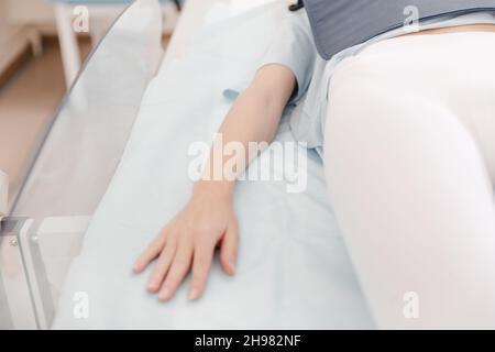 Focus on the hand of a patient in hospital ward. Female patient in a modern hospital room lying on the bed. Doctor taking x-ray of patient lying on Stock Photo