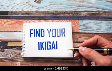 find your ikigai, reminder text is written by a woman's hand in a notebook - the Japanese concept of the reason for the existence of the purpose of li Stock Photo