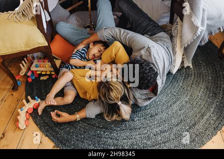 Top view of a little boy having fun with his mom and dad in their play area. Young boy laughing cheerfully while playing with his parents. Family of t