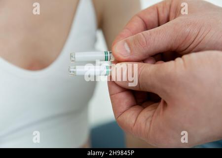 Doctor holds in hands small ampoules. Close up of small ampoule with a vaccine in the doctor hand. Holding test tube for allergy test. Allergy Testing Stock Photo