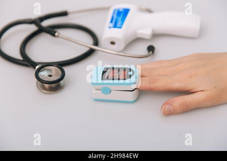Stethoscope, pulse oximeter and thermometer gun on white background. Phonendoscope. Infrared isometric thermometer gun to check body temperature for Stock Photo
