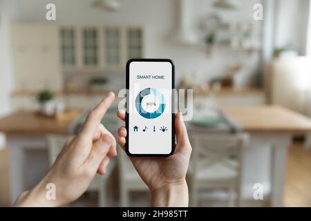 Close up cropped woman holding smartphone, using smart home app Stock Photo