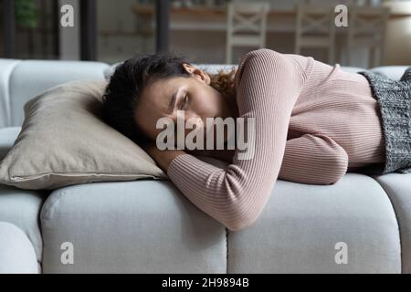 Close up unhappy woman lying on couch at home alone Stock Photo