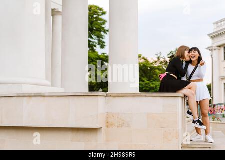 Multiracial two women talking and smiling while walking together outdoors Stock Photo