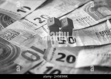 table covered with Euro banknotes with houses on top. Real estate investment concept Stock Photo