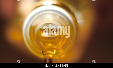 Extreme macro of olive oil poured from an original bottle. Stock footage. Close-up of oil pouring out of the bottle. Stock Photo
