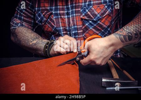 Artist working with leather creates quality product of leather in his work area Stock Photo
