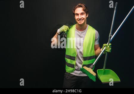 Smiling cleaner hold rubbish bag, broom and scoop Stock Photo
