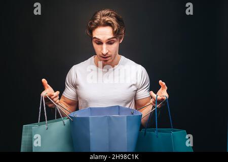 Surprised man looking in opened shopping bag Stock Photo