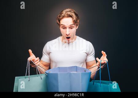Shocked man looking in opened shopping bag Stock Photo
