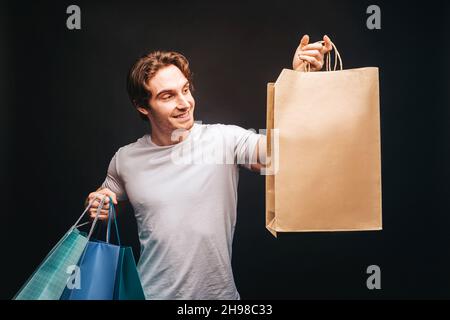 Young european man choosing gift in shopping bags Stock Photo