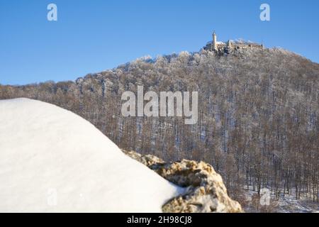 Castle also Stronghold (Teck) in winter on a clear evening with blue sky, many trees on the hill, huge rock with snow in the foreground. Germany, Owen Stock Photo