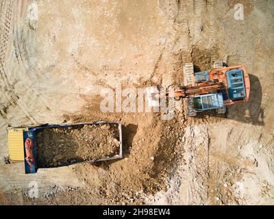 excavator and construction truck at site - top drone view Stock Photo