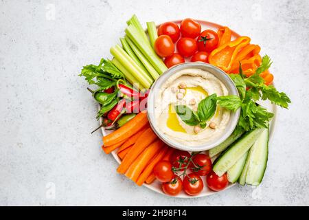 Hummus platter with assorted snacks. Hummus in bowl and vegetables sticks. Plate with Middle Eastern. Party, finger food. Top view. Vegan, hummus dip Stock Photo
