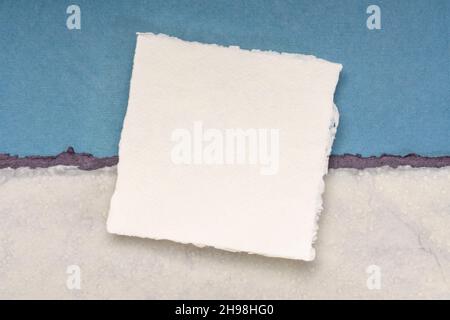 Small Square Sheet Of Blank White Khadi Paper Against Blue Rag