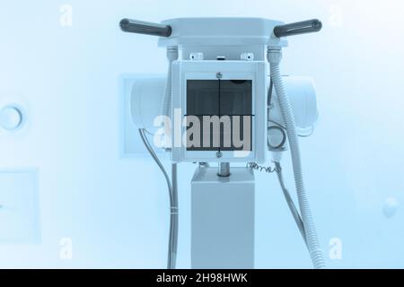 X-ray department in modern hospital. Radiology room with scan machine with empty bed. Technician adjusting an x-ray machine. Scanning chest, heart Stock Photo