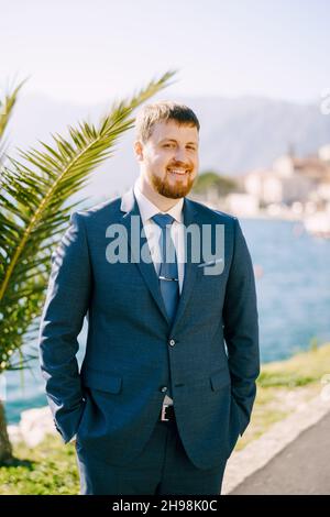Red-haired man in a blue suit stands near a palm tree. Portrait Stock Photo