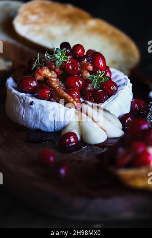 Baked Camembert Brie cheese with a cranberry, honey, balsamic vinegar and nut relish and garnished with thyme. Served with toasted bread slices. Selec Stock Photo