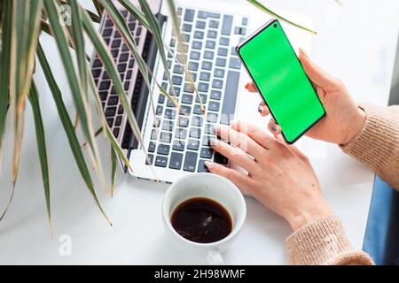 Young woman's hands scrolling and checking her phone. Focus on the mobile phonechromakey, green screen on screen. Stock Photo