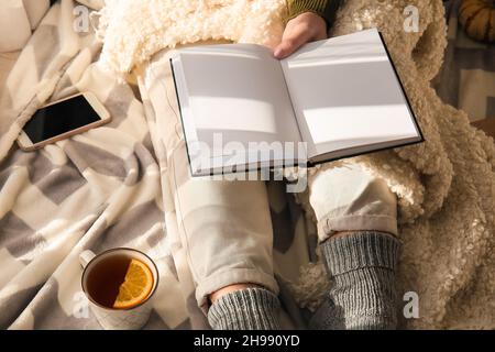 Woman sitting on floor and holding opened book with blank pages in room Stock Photo