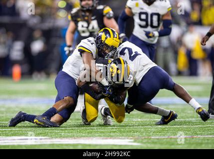 Indianapolis, Indiana, USA. 04th Dec, 2021. Michigan defenders Nikhai Hill-Green (41) and Brad Hawkins (2) makes the tackle on Iowa running back Tyler Goodson (15) during NCAA Football game action between the Michigan Wolverines and the Iowa Hawkeyes at Lucas Oil Stadium in Indianapolis, Indiana. Michigan defeated Iowa 42-3. John Mersits/CSM/Alamy Live News Stock Photo