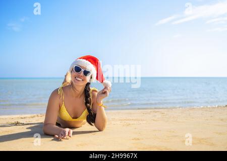 happy woman in santa hat and sunglasses lying on sand beach Stock Photo