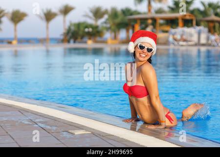 happy young woman in santa hat in swimming pool Stock Photo