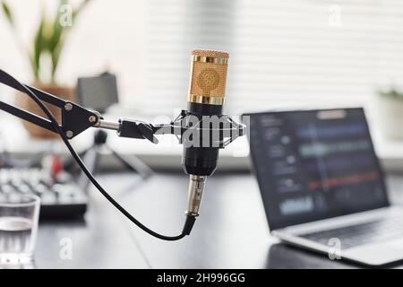 Close up of gold professional microphone in recording studio with laptop in background, copy space Stock Photo