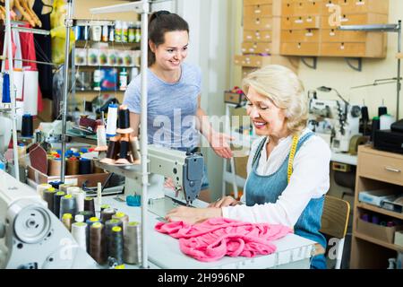 Two attentive women tailors working with sewing machines Stock Photo