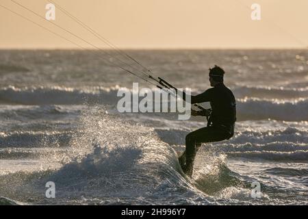 Silhouetted kite surfer at the ever popular West Wittering beach in West Sussex Stock Photo