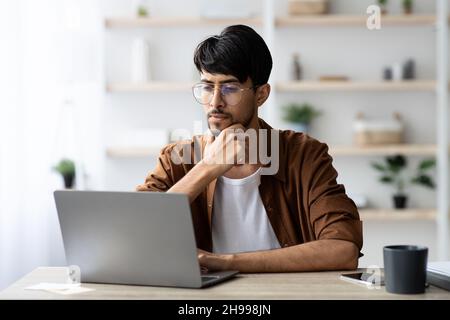 Pensive arabic man employee working on modern notebook Stock Photo