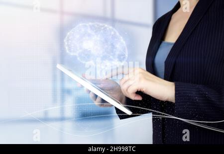 Digital Brain Artificial intelligence. Hand touch white tablet with digital hologram Brain sign on light blurred background. Science and artificial in Stock Photo