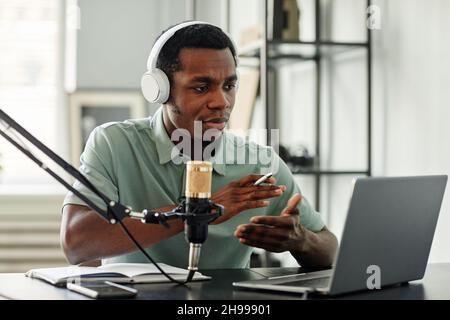 Portrait of African-American man speaking to camera while recording podcast at home Stock Photo