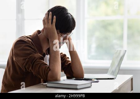 Sad middle eastern man suffering from headache at office Stock Photo