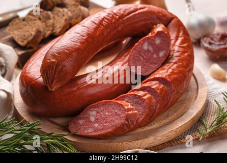 Smoked, spicy sausage with fresh basil close-up. Side view, horizontal. Stock Photo