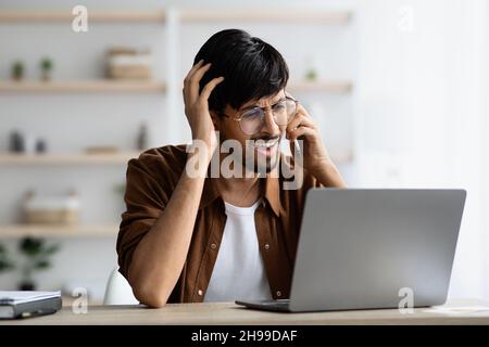 Irritated indian man independent contractor having phone conversation Stock Photo