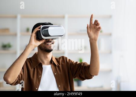 Young man using VR glasses, pointing at camera, closeup portrait Stock Photo