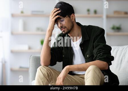 Indian guy touching his head, suffering from headache, copy space Stock Photo