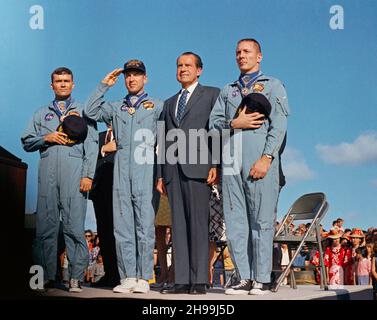 President Richard M. Nixon and the Apollo 13 crew members pay honor to the United States flag during the post-mission ceremonies at Hickam Air Force Base, Hawaii. Astronauts James A. Lovell Jr., (United States Navy Captain, salutes the flag) commander; John L. Swigert Jr., command module pilot (right); and Fred W. Haise Jr., lunar module pilot (left), were presented the Presidential Medal of Freedom by the Chief Executive. The Apollo 13 splashdown occurred at 12:07:44 p.m. (CST), April 17, 1970, about a day and a half prior to the award presentation. Stock Photo