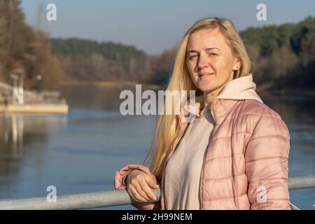 portrait of a blonde girl on the background of the river and the autumn forest Stock Photo